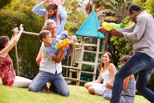 Texto alternativo: pessoas diversas com filhos brincando com água no quintal - poupar dinheiro com filhos - Assaí Atacadista