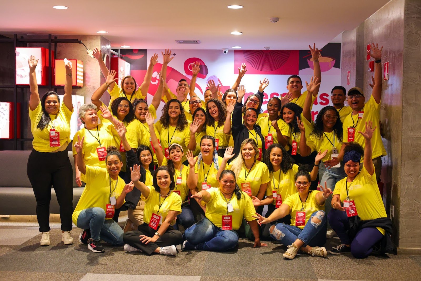 pessoas diversas felizes com os braços pra cima usando camisetas amarelas - Prêmio Academia Assaí - Instituto Assaí Atacadista