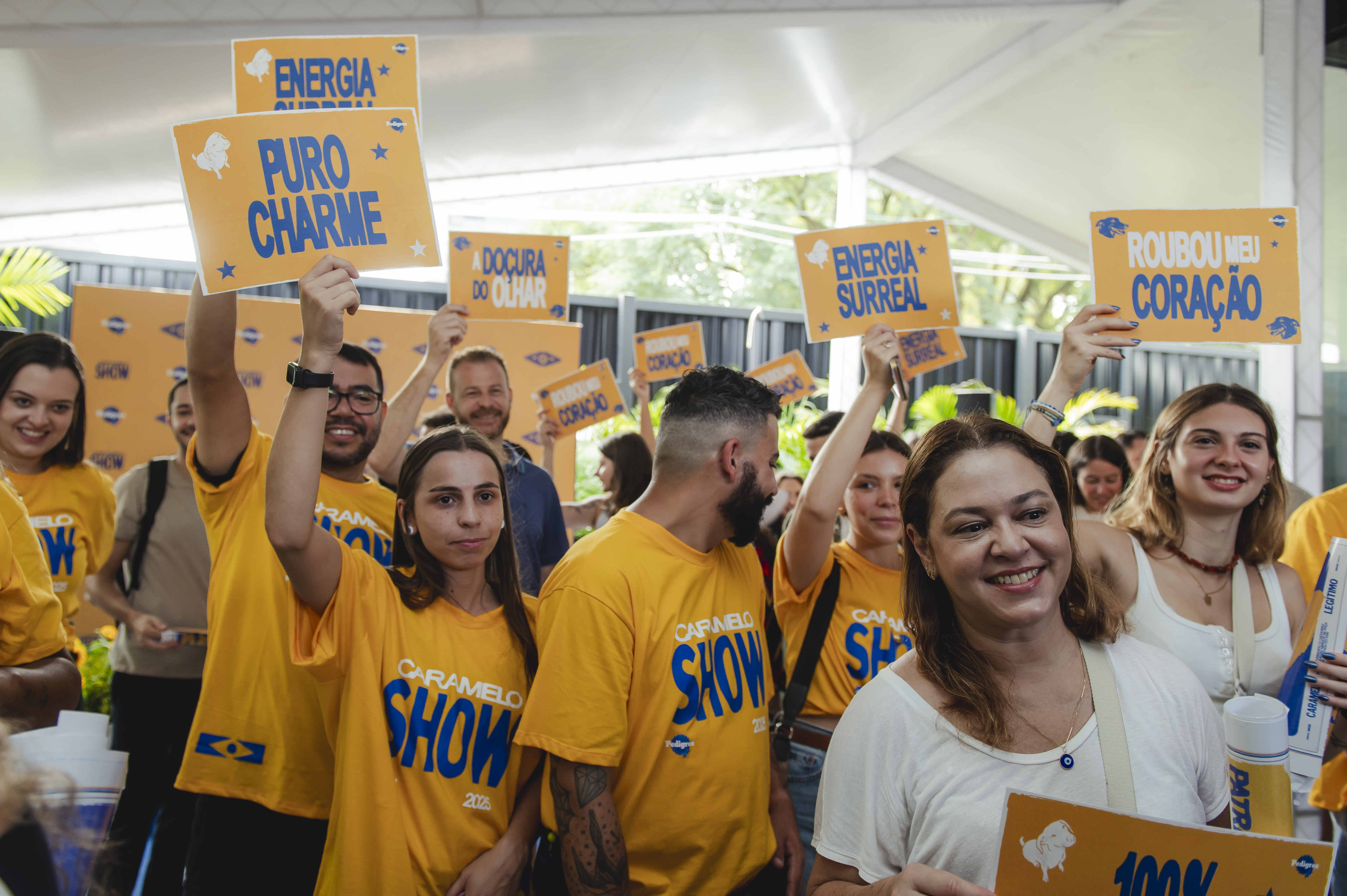 Pessoas no Caramelo Show segurando placas com texto - Pedigree - Fornecedores do Assaí Atacadista.jpg