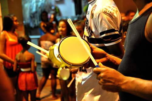 pessoas tocando instrumentos com a mão em uma rua à noite - crianças no Carnaval - Assaí Atacadista - Imagem: Shutterstock