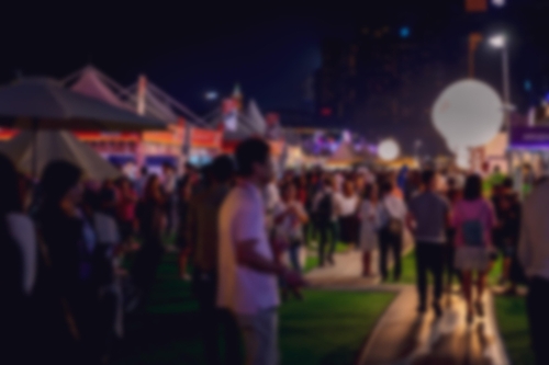 praça com barracas de comércio cheio de pessoas em uma cidade à noite com a imagem borrada - Assaí Atacadista - atividades noturnas - Imagem Shutterstock