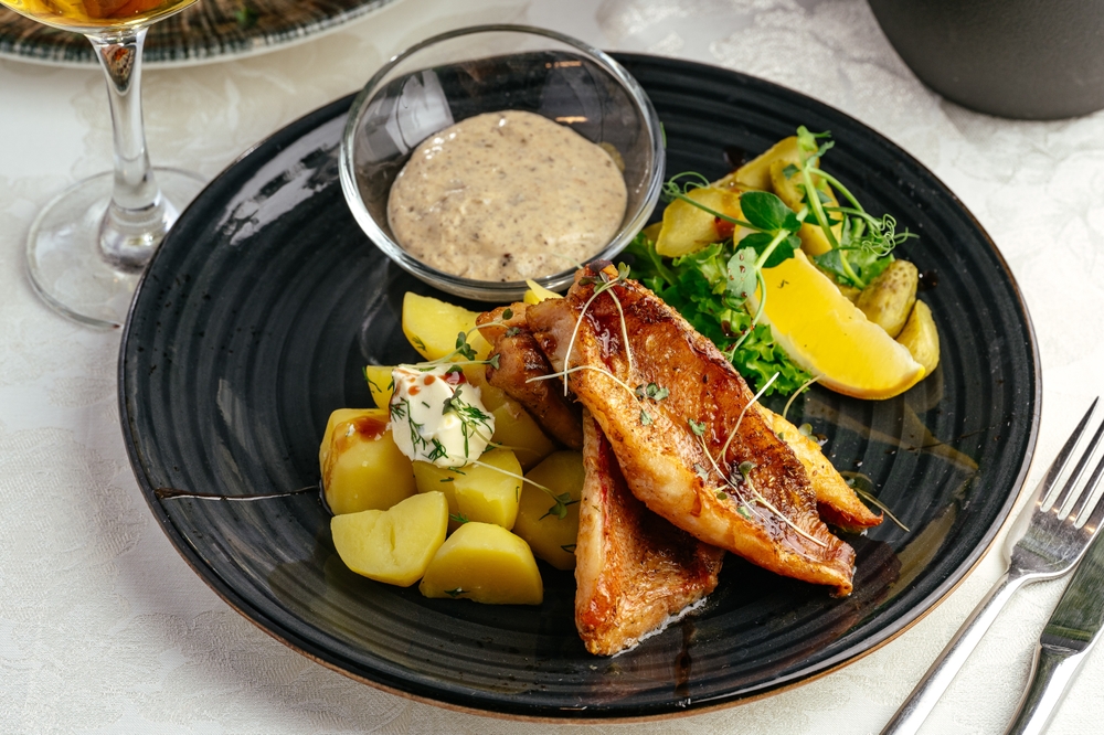 prato preto com uma refeição de peixe e batatas - restaurante lucrativo - Assaí Atacadista
