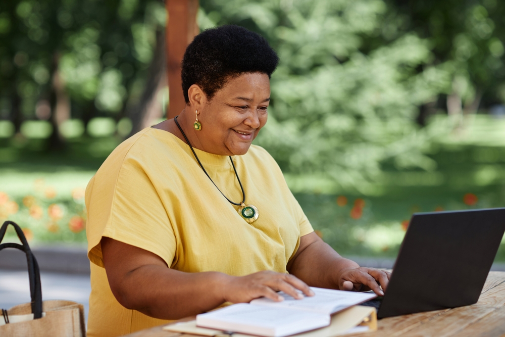 senhora plus size negra feliz estudando online - Dia do Trabalhador - Assaí Atacadista