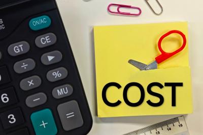 calculadora e papel amarelo sendo cortado por uma mini tesoura representando uma redução de custos - Assaí Atacadista - Imagem Shutterstock