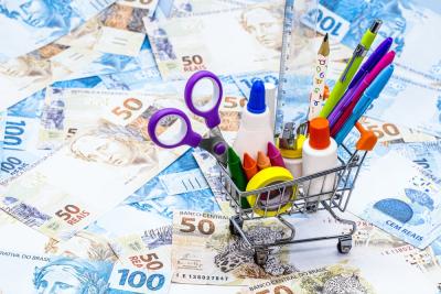 carrinho de compras com materiais escolares e dinheiro no chão - volta as aulas - Assaí Atacadista