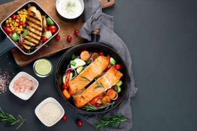 fundo preto com alimentos e duas panelas, uma com peixe grelhado e vegetais e a outra com frango grelhado e vegetais - Quarta-feira de Cinzas - Assaí Atacadista - Imagem: Shutterstock