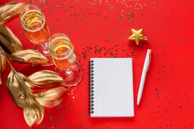fundo vermelho com taças de champanhe e um bloco de notas em branco com uma caneta - resoluções de Ano-Novo - Assaí Atacadista