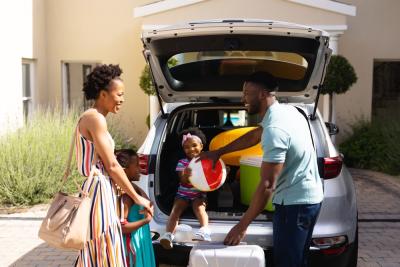 homem mulher e crianças negras felizes colocando malas em um carro-Assaí Atacadista-viagem bate e volta