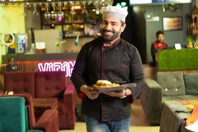 homem sorrindo segurando um prato de comida em um restaurante - Assaí Atacadista - Food Service