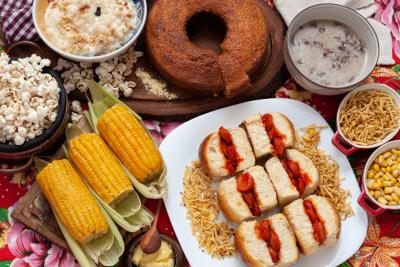 mesa com diferentes pratos como milho cozido bolo pipoca e mini cachorro quente-festas com saúde-Assaí Atacadista