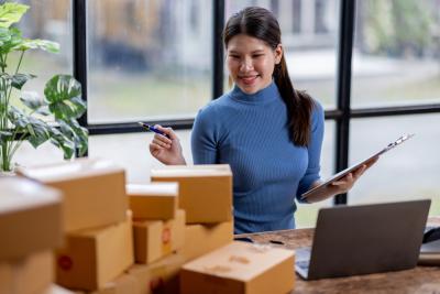 mulher empreendedora asiatica olhando para caixas na mesa - franquias populares - Assaí Atacadista