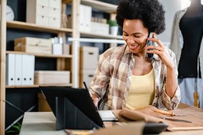 mulher empreendedora negra falando no celular enquanto olha para um tablet - Assaí Atacadista - quarto trimestre