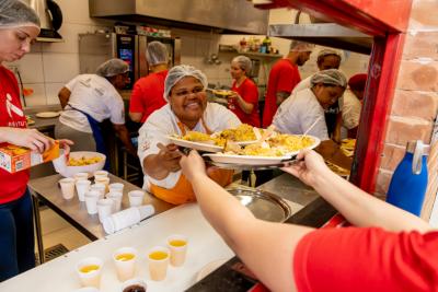 mulher negra feliz entregando um alimento para outra pessoa-Relatório Anual 2025-Instituto Assaí