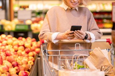 mulher segurando um celular e um carrinho em um mercado-Assaí Atacadista-negócio