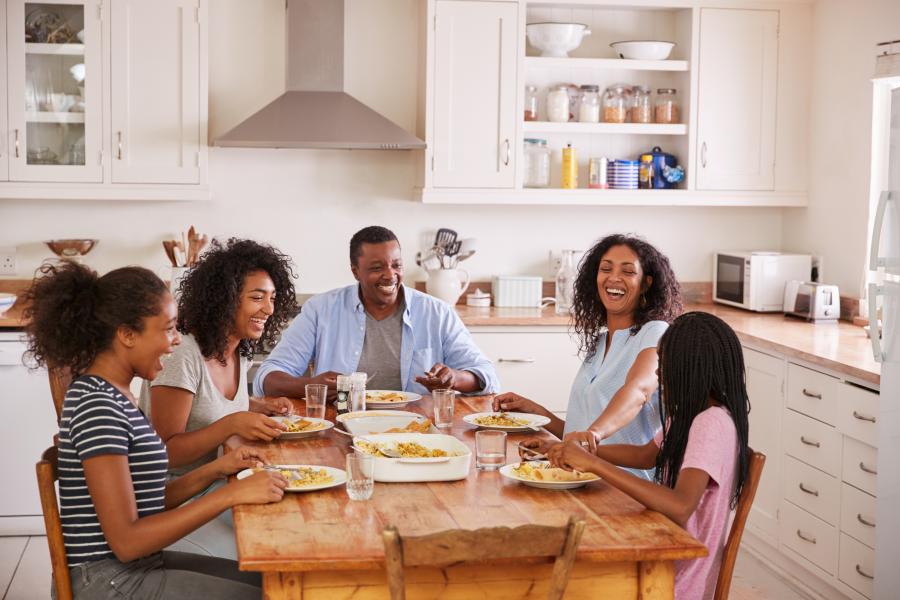 família negra feliz fazendo uma refeição na mesa da cozinha - almoço de páscoa - Assaí Atacadista