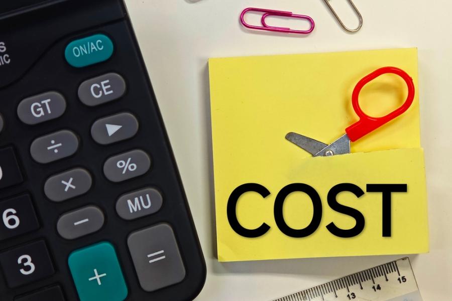 calculadora e papel amarelo sendo cortado por uma mini tesoura representando uma redução de custos - Assaí Atacadista - Imagem Shutterstock