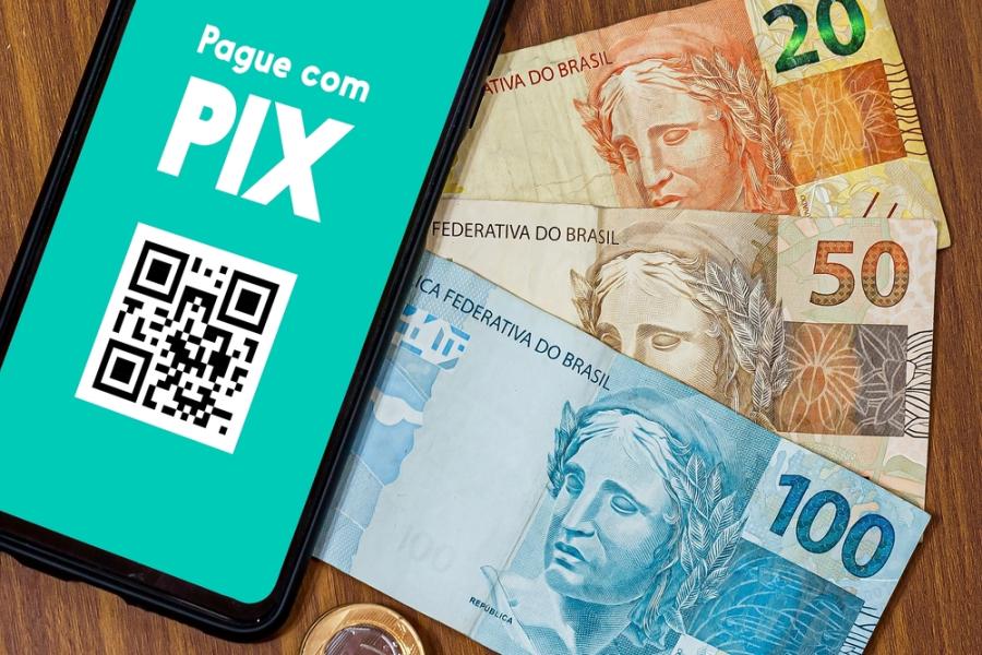 celular com um QR Code em uma tela de Pix com células de dinheiro de vinte, cinquenta e cem reais - Assaí Atacadista - pagamento com Pix