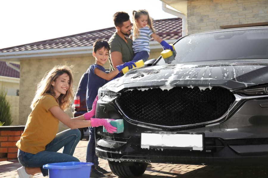 família branca com uma mulher, duas crianças e um homem lavando um carro preto - cuidados com veículos - Assaí Atacadista