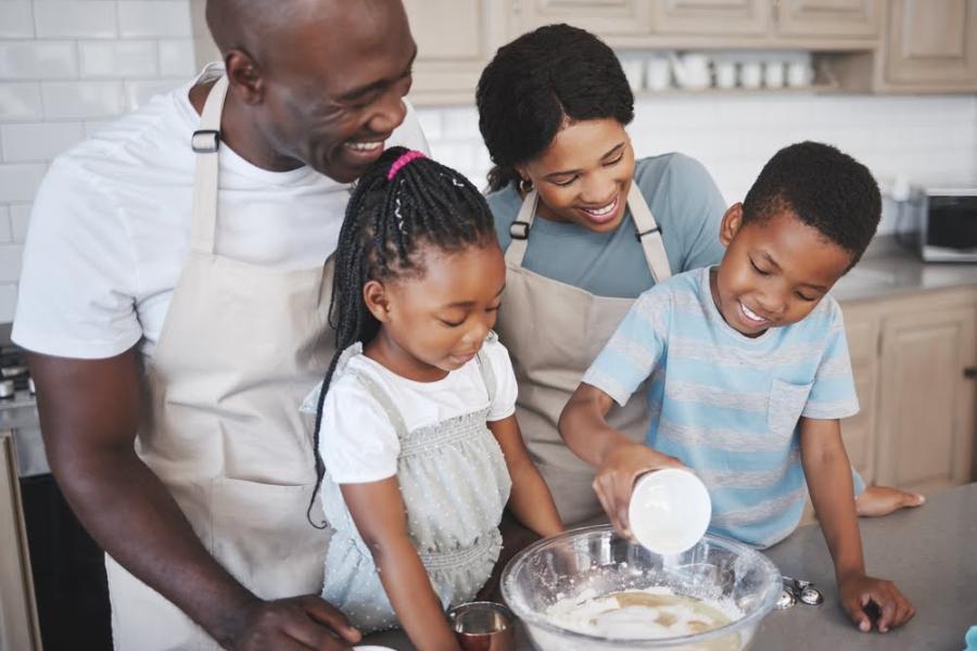 familia negra feliz cozinhando com um casal de filhos - Dia da Consciência Negra - Assaí Atacadista - culinária afro-brasileira