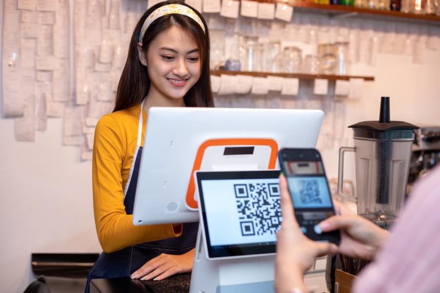 funcionária no caixa com um cliente lendo um qrcode - formas de pagamento - Assaí Atacadista