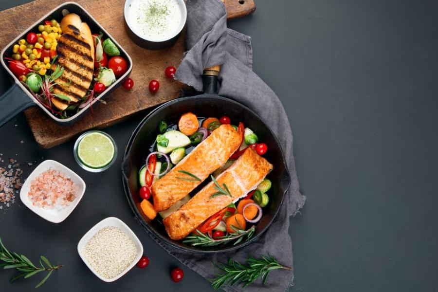 fundo preto com alimentos e duas panelas, uma com peixe grelhado e vegetais e a outra com frango grelhado e vegetais - Quarta-feira de Cinzas - Assaí Atacadista - Imagem: Shutterstock