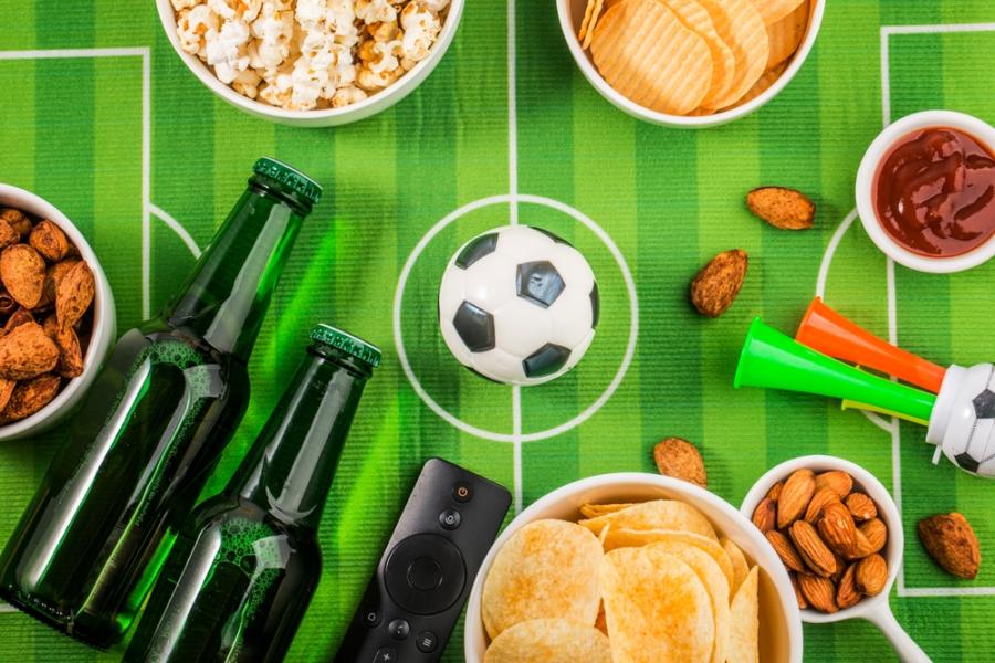 gramado de futebol com bebidas e snacks ao lado de uma bola-torcedores de futebol-Assaí Atacadista