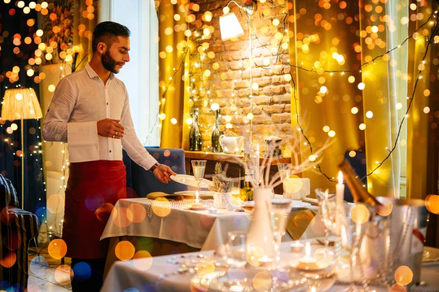homem branco garçom em um restaurante com decorações natalinas - Assaí Atacadista - marketing sensorial
