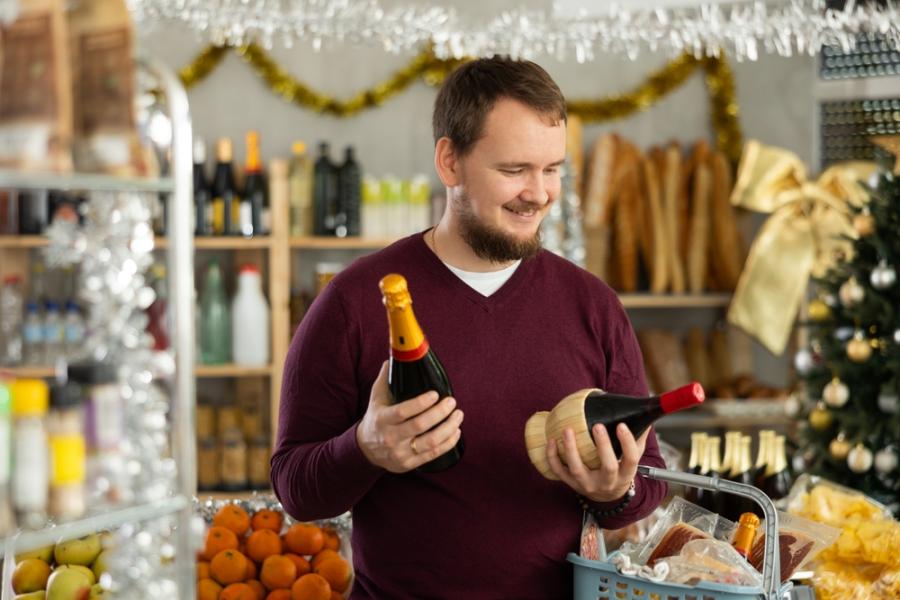 homem branco segurando garrafas de champanhe nas mãos em uma loja decorada-Assaí Atacadista-compras fim de ano