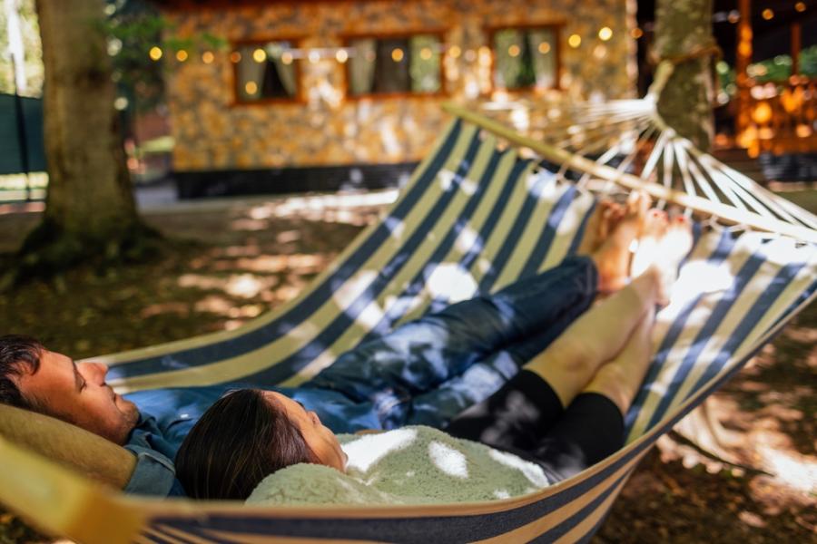 homem e mulher relaxando deitados em uma rede na sombra com pontinhos de sol - fugir do carnaval- Assaí Atacadista