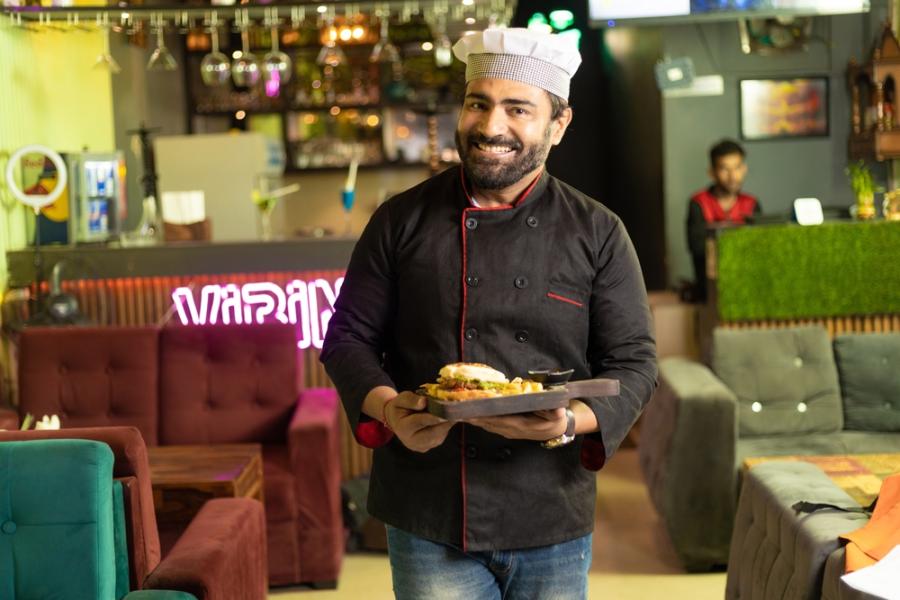 homem sorrindo segurando um prato de comida em um restaurante - Assaí Atacadista - Food Service