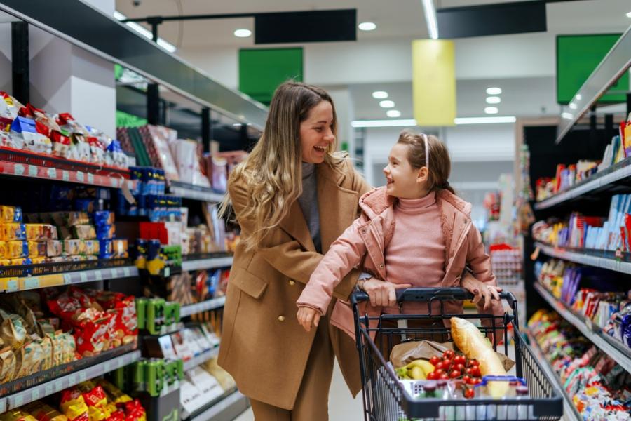 mãe com filha felizes em um carrinho de compras no corredor de um mercado - dia do consumidor - assaí atacadista
