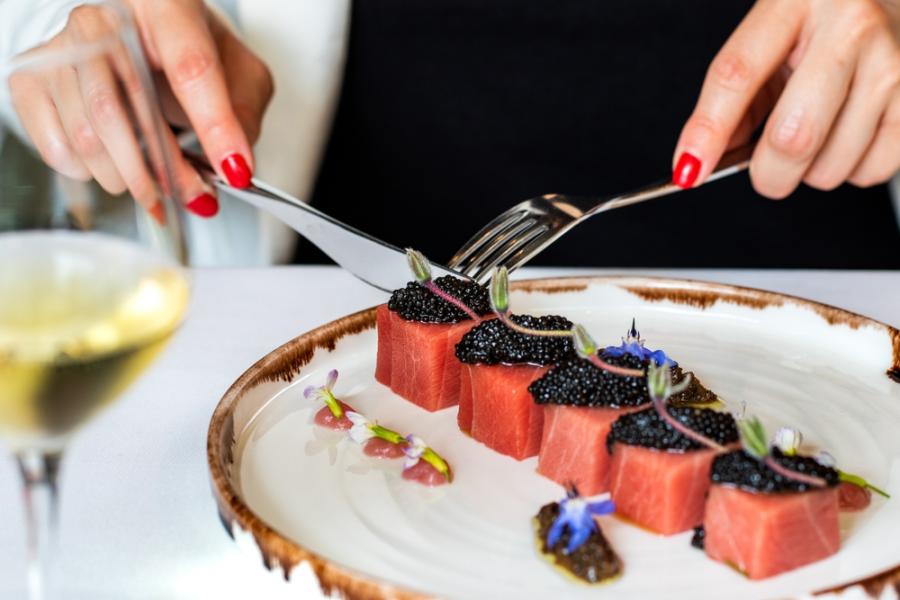 mãos brancas femininas fazendo uma refeição sofisticada com salmão e caviar em um prato - menu degustação - Assaí Atacadista
