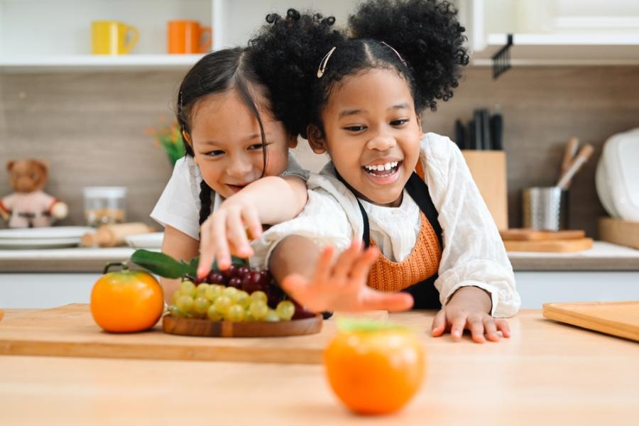 meninas crianças felizes na cozinha com frutas na mesa - frutas para crianças - Assaí Atacadista