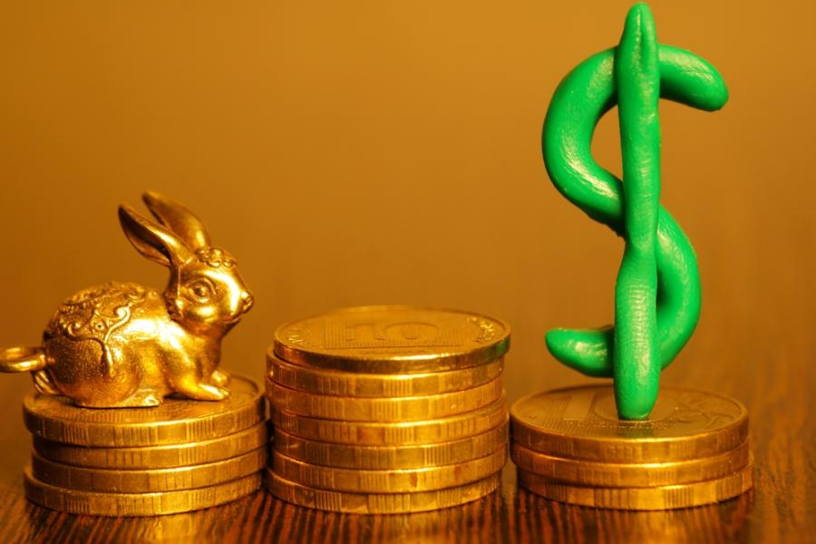 moedas empilhadas com um coelho dourado e um símbolo de cifrão verde - renda extra na páscoa - assaí atacadista