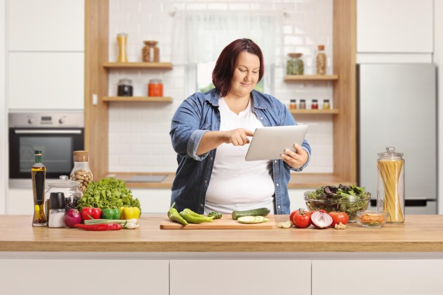 mulher branca plus size na cozinha com vários alimentos - beleza e alimentação - Assaí Atacadista