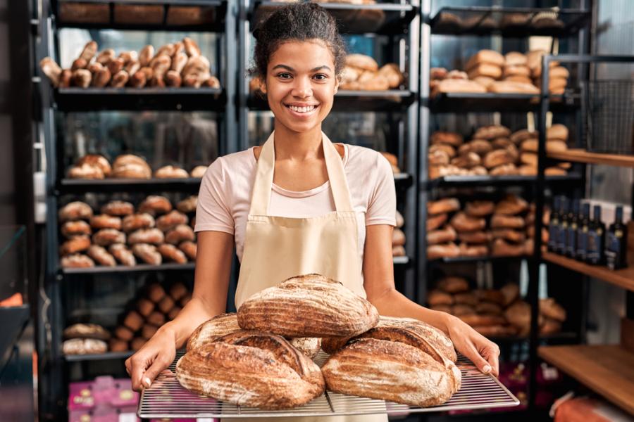 mulher negra em uma panificadora segurando pães - pão - Assaí Atacadista