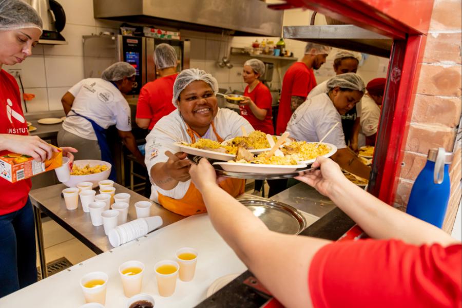 mulher negra feliz entregando um alimento para outra pessoa-Relatório Anual 2025-Instituto Assaí