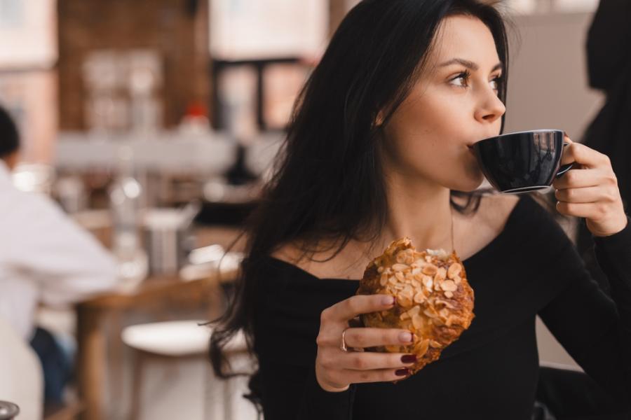 mulher tomando café e comendo em uma lanchonete - Assaí Atacadista