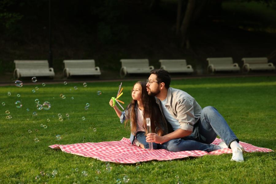 pai e filha brincando com bolhas de sabão em uma praça - Assaí Atacadista - atividades familiares