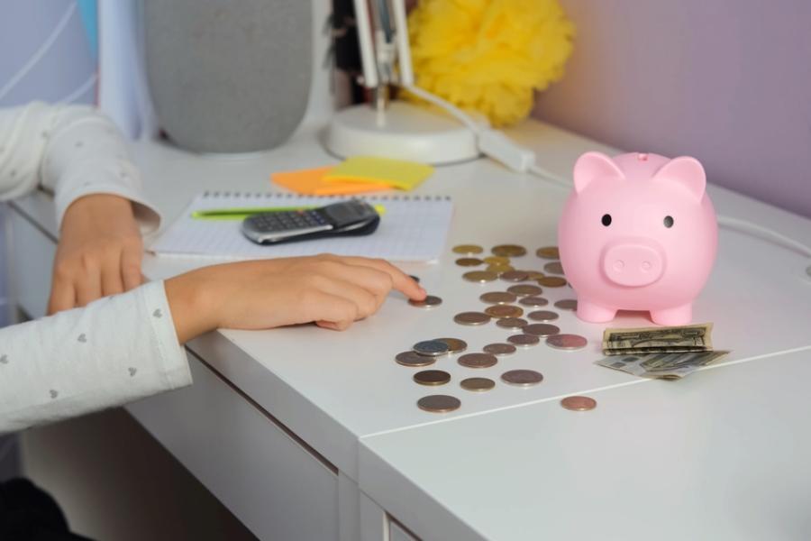 pessoa branca contando moedas em uma mesa com um cofre de porquinho rosa-voltas a economizar-Assaí Atacadista