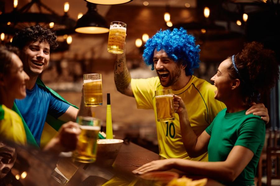 pessoas caracterizadas com as cores da bandeira do Brasil em um bar brindando-camarote vip-Assaí Atacadista