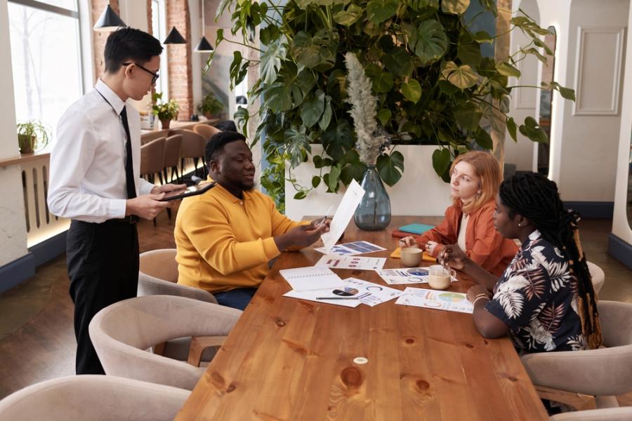 pessoas diversas conversando sobre gestão de restaurante com papeis na mesa - Assaí Atacadista