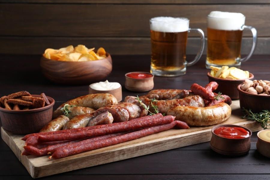 tábua com carnes em uma mesa com copos de cerveja e outros petiscos em potes-churrasco perfeito-Assaí Atacadista