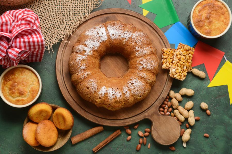 Mesa com comidas de São João e um bolo no centro - Assaí Atacadista