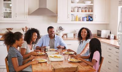 família negra feliz fazendo uma refeição na mesa da cozinha - almoço de páscoa - Assaí Atacadista
