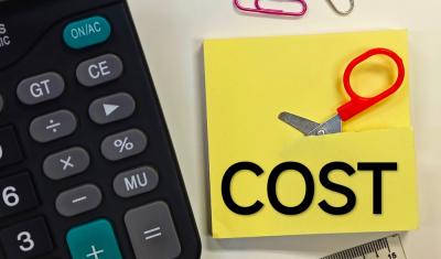 calculadora e papel amarelo sendo cortado por uma mini tesoura representando uma redução de custos - Assaí Atacadista - Imagem Shutterstock