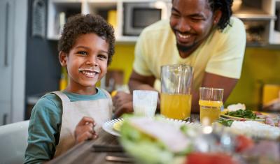 criança tomando iogurte em uma mesa farta com o pai negro do lado-Assaí Atacadista-Danone