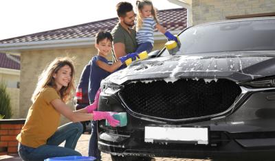família branca com uma mulher, duas crianças e um homem lavando um carro preto - cuidados com veículos - Assaí Atacadista