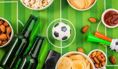 gramado de futebol com bebidas e snacks ao lado de uma bola-torcedores de futebol-Assaí Atacadista