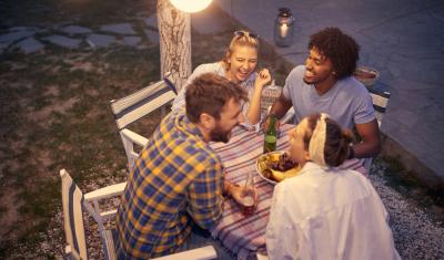 grupo de 4 amigos rindo em uma mesa ao ar livre - atividades noturnas - Assaí Atacadista